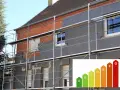 Dom w trakcie ocieplenia domów. Scaffolding otacza budynek, na którym montowane są płyty izolacyjne. W rogu wstawka z klasą energetyczną.