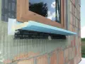 Fragment okna w trakcie ciepłego montażu. Widoczna taśma uszczelniająca i izolacja pod parapetem.