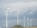 Wiatraki na tle pochmurnego nieba. Zastanawiasz się, ile wiatrak produkuje energii na godzinę?