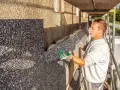 Pracownik montuje płyty izolacyjne na ścianie budynku. To etap ocieplenia domu, który zapewni komfort i oszczędność energii.