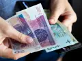 Dłonie trzymają polskie banknoty 20 zł i 100 zł, gotowe do zapłaty. Może to być część wypłaty ryczałtu energetycznego.