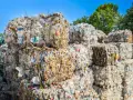 Ogromne bele sprasowanych plastikowych butelek tworzą krajobraz wysypiska śmieci. Kolorowe nakrętki dodają im niepokojącego uroku.