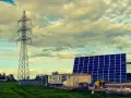 Własny prąd bez podłączenia do sieci: duża farma fotowoltaiczna obok wieży energetycznej i przyczepy mieszkalnej.