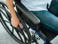 Osoba na wózku trzymająca koło. Ulga na prąd dla niepełnosprawnych Tauron to wsparcie dla osób potrzebujących.