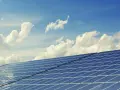 Panele słoneczne na tle błękitnego nieba z chmurami. To dowód na liczne zalety energii słonecznej – czystej i odnawialnej.