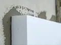 Biały styropian przyklejany do ściany. Materiał izolacyjny, który pomoże w ociepleniu domu, a nie styrobeton.