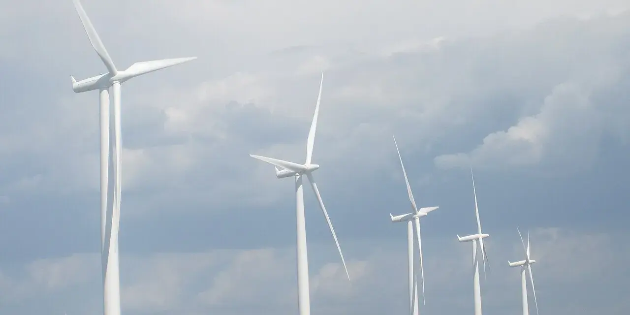 Wiatraki na tle pochmurnego nieba. Zastanawiasz się, ile wiatrak produkuje energii na godzinę?