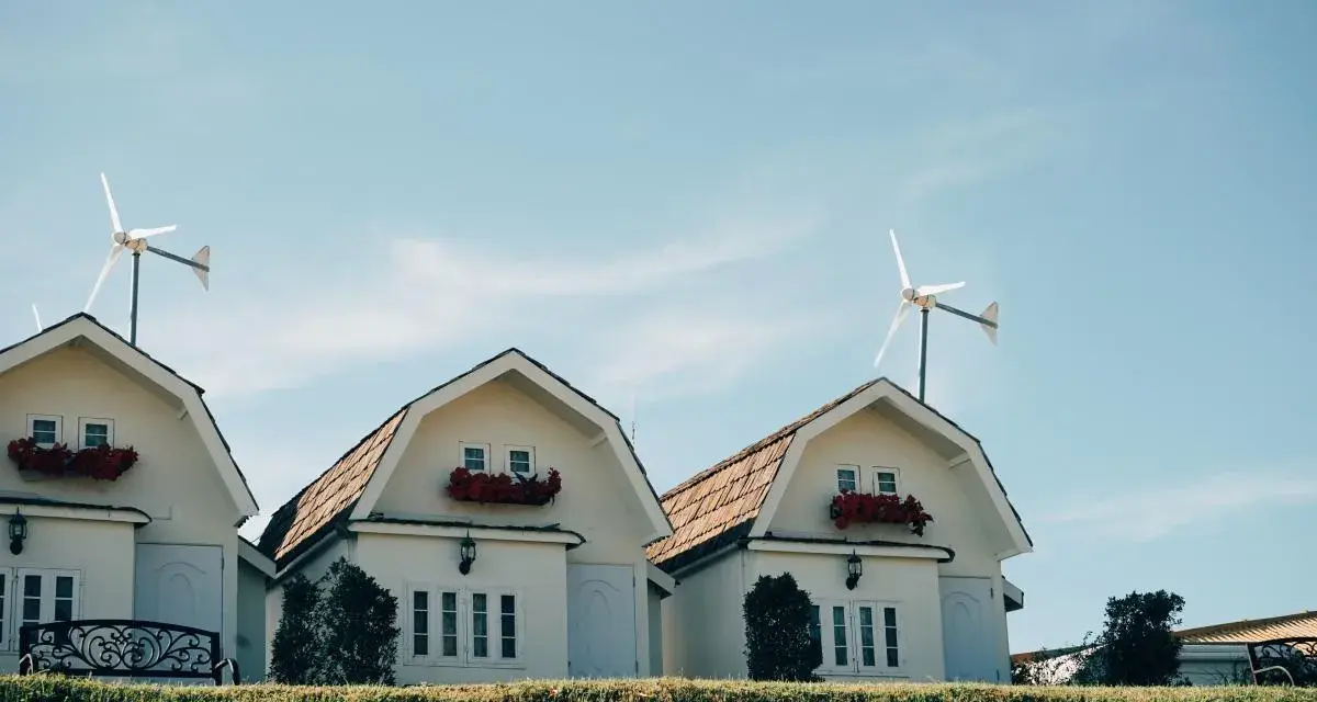 Domy z czerwonymi kwiatami i turbina wiatrowa bez pozwolenia na dachu.