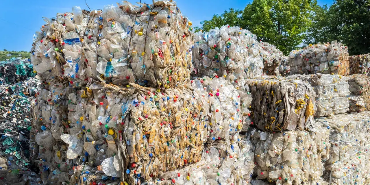 Ogromne bele sprasowanych plastikowych butelek tworzą krajobraz wysypiska śmieci. Kolorowe nakrętki dodają im niepokojącego uroku.