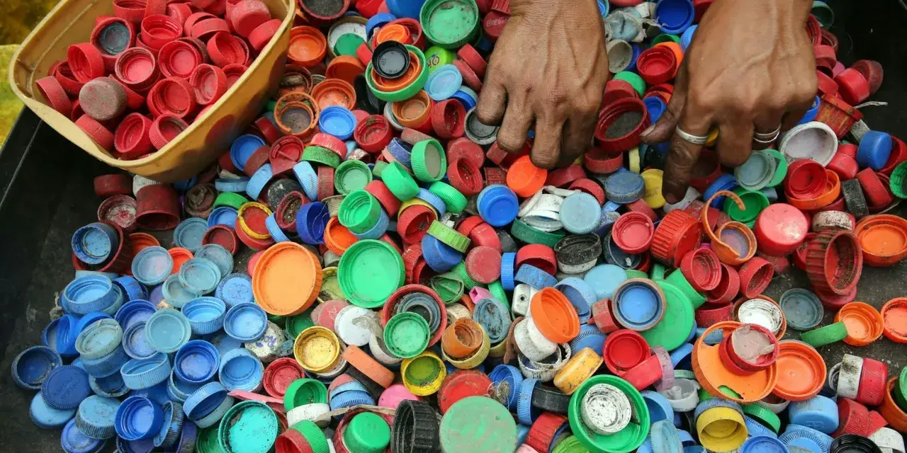 Ręce zbierają kolorowe nakrętki, pokazując, dlaczego zbiera się nakrętki – dla recyklingu i pomocy potrzebującym.