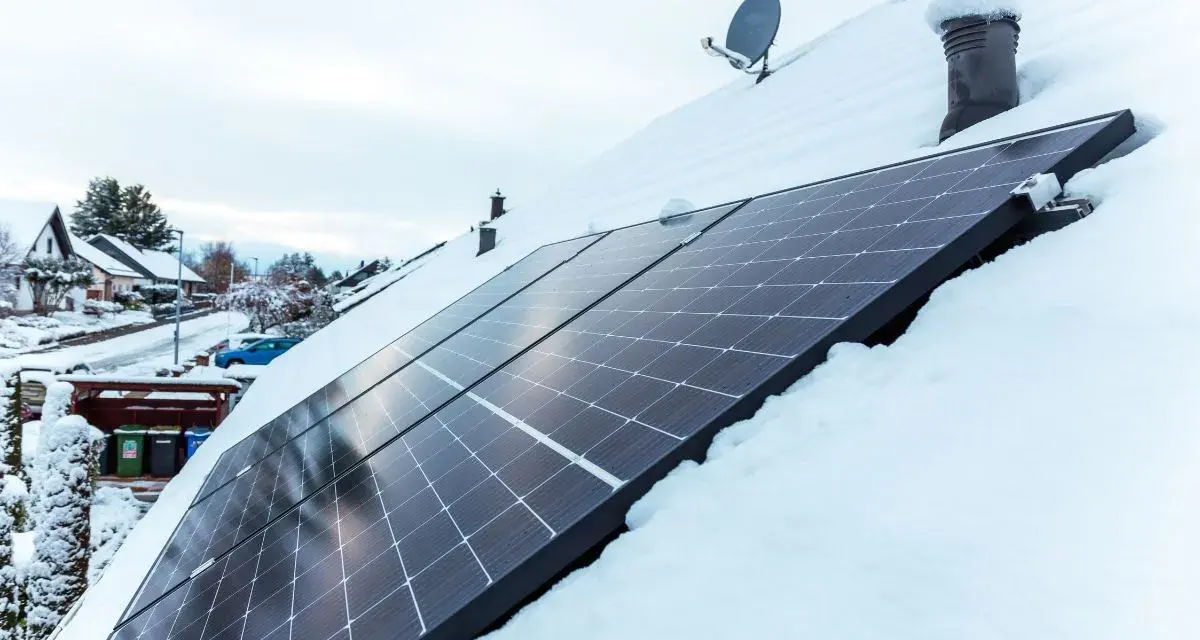 Panele fotowoltaiczne na dachu pokrytym śniegiem. Nawet zimą, przy odpowiednim nachyleniu, mogą produkować energię.
