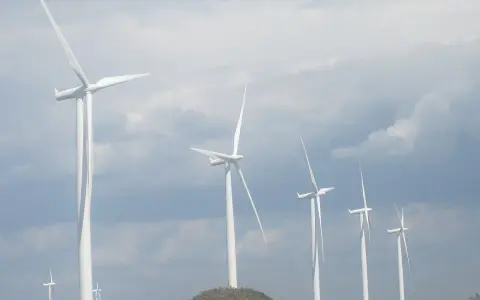 Wiatraki na tle pochmurnego nieba. Zastanawiasz się, ile wiatrak produkuje energii na godzinę?