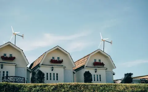 Domy z czerwonymi kwiatami i turbina wiatrowa bez pozwolenia na dachu.