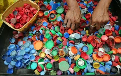 Ręce zbierają kolorowe nakrętki, pokazując, dlaczego zbiera się nakrętki – dla recyklingu i pomocy potrzebującym.