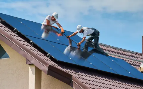 Dwóch mężczyzn montuje panele fotowoltaiczne na dachu. To przyszłość energetyki w Polsce.