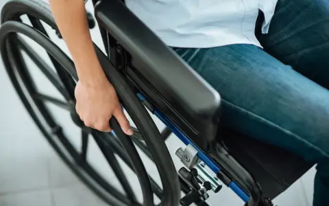 Osoba na wózku trzymająca koło. Ulga na prąd dla niepełnosprawnych Tauron to wsparcie dla osób potrzebujących.