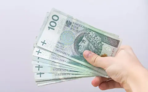 Dłoń trzyma stos banknotów 100 zł. Czy to zapowiedź bonu energetycznego dla każdego?