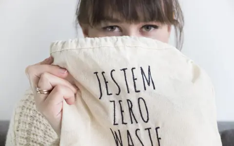Sylwia Majcher, z uśmiechem ukrytym za torbą z napisem "Jestem Zero Waste", pokazuje swoje zaangażowanie w ekologię.