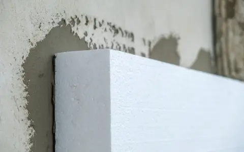 Biały styropian przyklejany do ściany. Materiał izolacyjny, który pomoże w ociepleniu domu, a nie styrobeton.