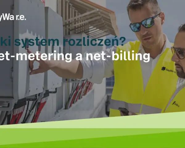 Dwóch mężczyzn w kamizelkach odblaskowych przy panelach, dyskutujących o systemach rozliczeń: net-metering a net-billing.