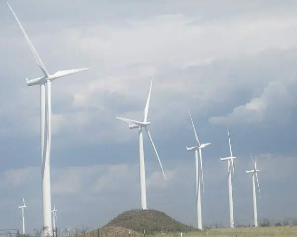 Wiatraki na tle pochmurnego nieba. Zastanawiasz się, ile wiatrak produkuje energii na godzinę?