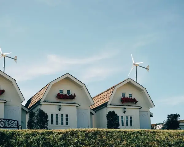 Domy z czerwonymi kwiatami i turbina wiatrowa bez pozwolenia na dachu.
