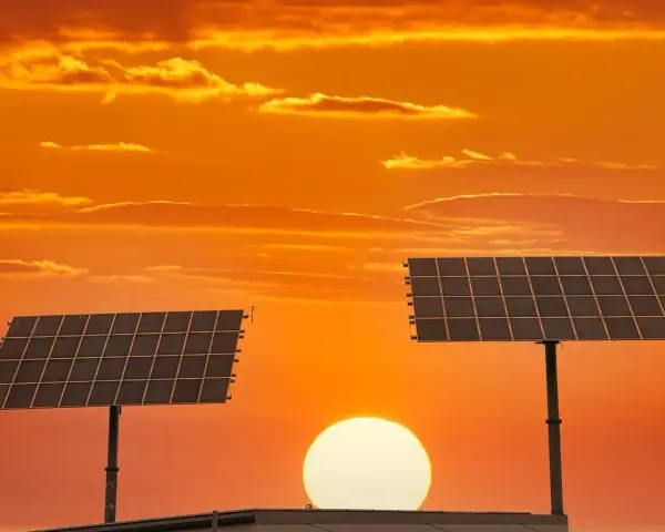 Dwa panele fotowoltaiczne na tle zachodzącego słońca. To pokazuje, co daje fotowoltaika – czystą energię ze słońca.