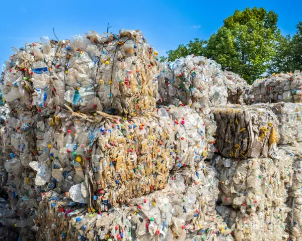Ogromne bele sprasowanych plastikowych butelek tworzą krajobraz wysypiska śmieci. Kolorowe nakrętki dodają im niepokojącego uroku.