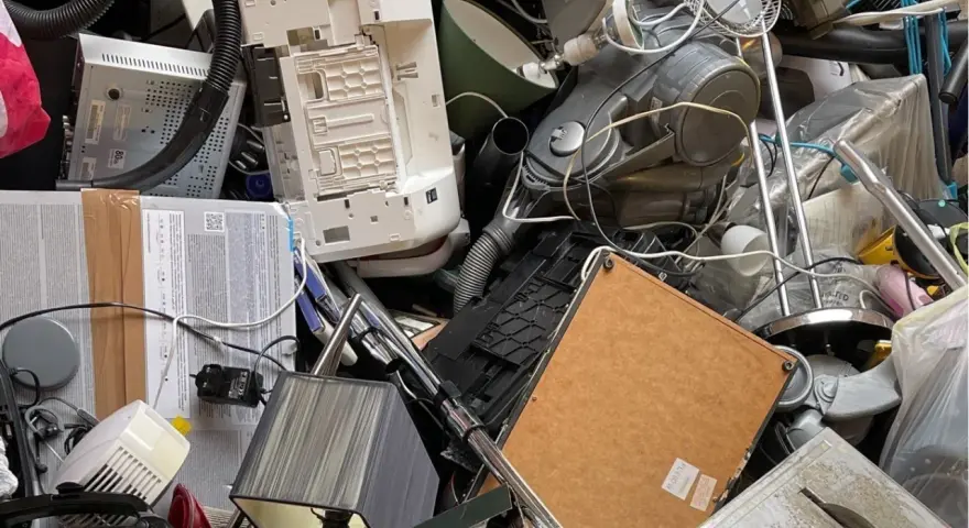 Stary sprzęt AGD, w tym odkurzacz i drukarka, tworzą stos. Zastanawiasz się, gdzie wyrzucić żelazko? To miejsce to idealny przykład elektrośmieci.