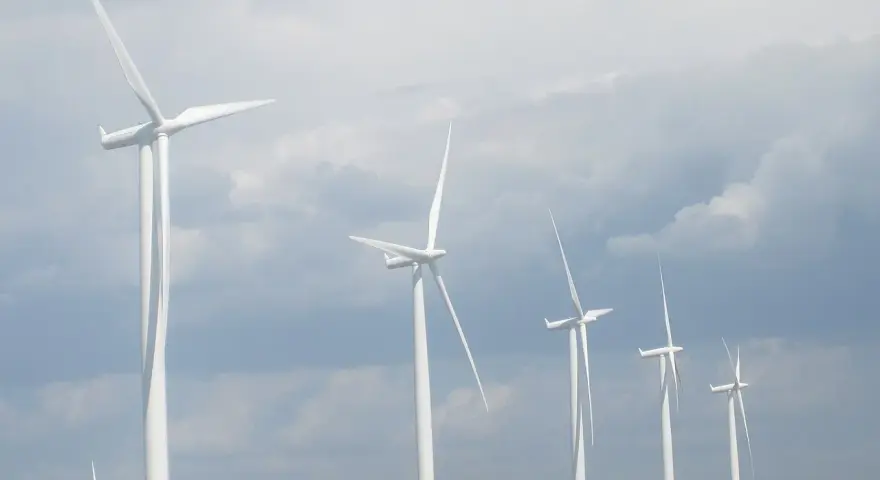 Wiatraki na tle pochmurnego nieba. Zastanawiasz się, ile wiatrak produkuje energii na godzinę?