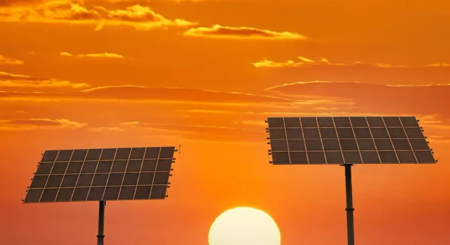 Dwa panele fotowoltaiczne na tle zachodzącego słońca. To pokazuje, co daje fotowoltaika – czystą energię ze słońca.