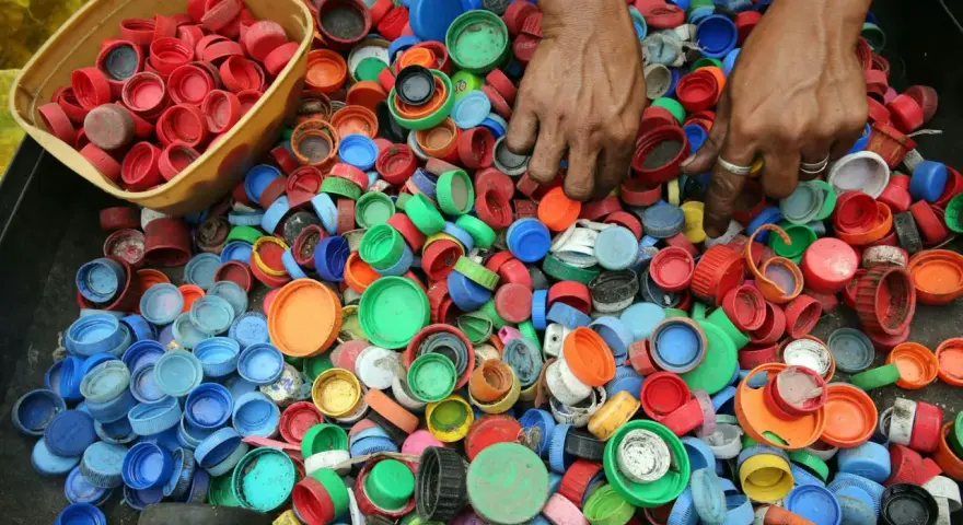 Ręce zbierają kolorowe nakrętki, pokazując, dlaczego zbiera się nakrętki – dla recyklingu i pomocy potrzebującym.