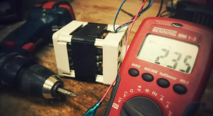 Narzędzia i transformator, potencjalne odpady elektroniczne, czekają na diagnozę multimetrem.