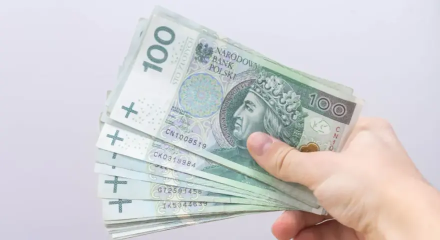 Dłoń trzyma stos banknotów 100 zł. Czy to zapowiedź bonu energetycznego dla każdego?