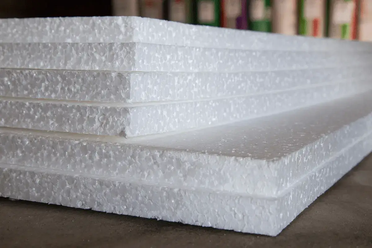Stos białych płyt styropianowych, które budzą pytanie: czy styropian to plastik? Materiał budowlany o lekkiej, spienionej strukturze.