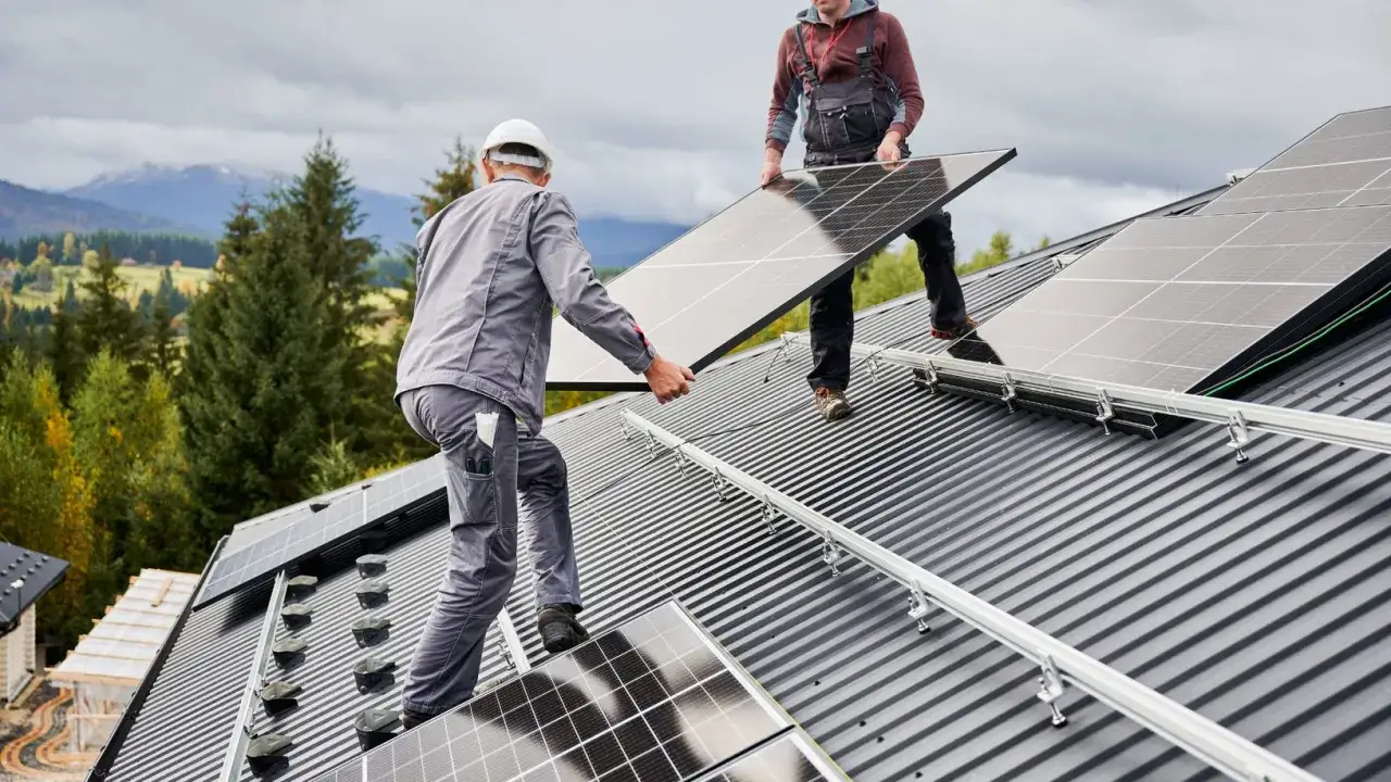 Przegląd instalacji fotowoltaicznej na dachu. Dwóch pracowników montuje panele słoneczne, przygotowując dom do produkcji czystej energii.