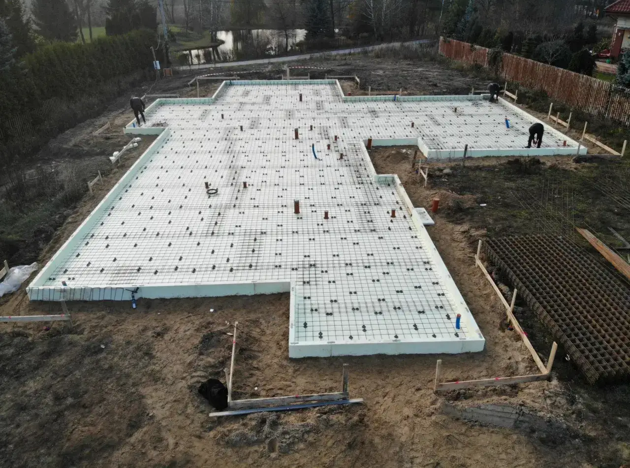 Budowa domu: przygotowana płyta fundamentowa zbrojona i izolowana, gotowa do zalania betonem.