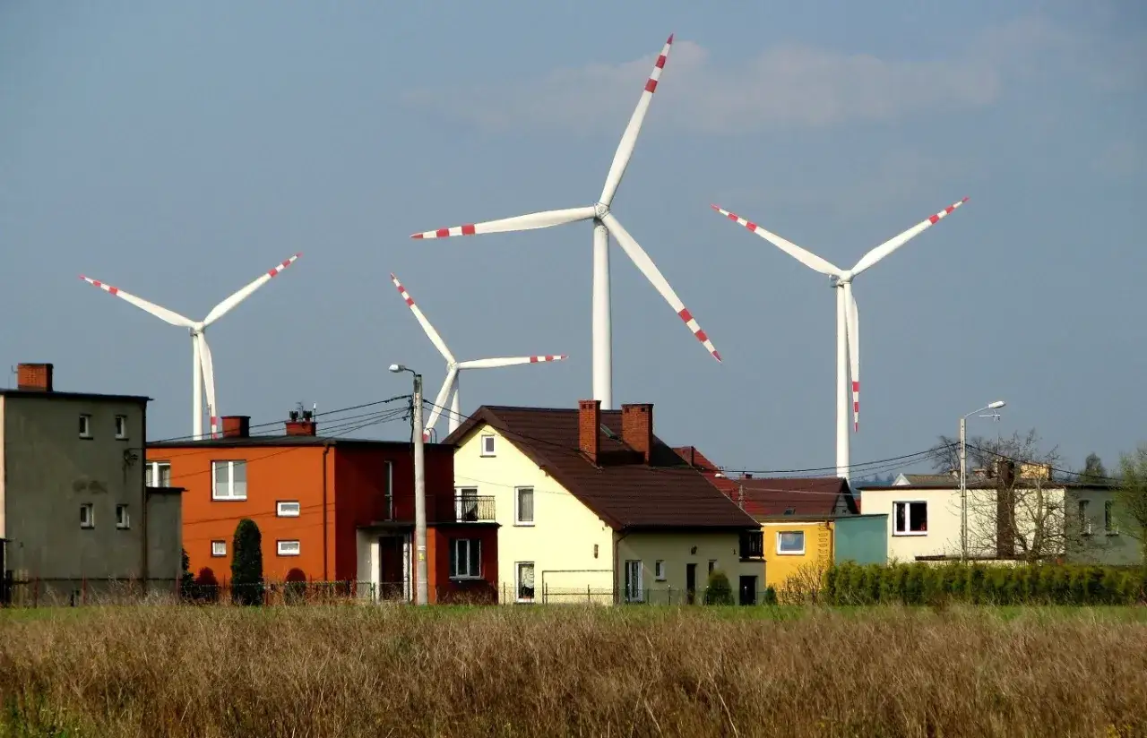 Wysokość wiatrak&oacute;w robi wrażenie na tle kolorowych dom&oacute;w i nieba.