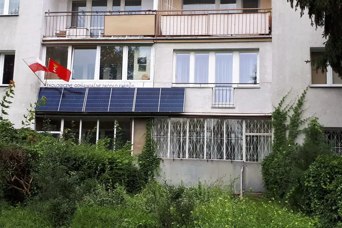 Zgoda na montaż paneli fotowoltaicznych na balkonie, obok flag Polski i Gdańska. Napis